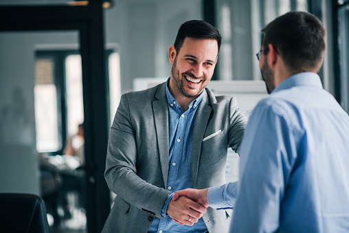 Portrait of cheerful young manager handshake with new employee. Portrait of cheerful young manager handshake with new employee.